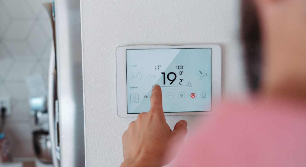 Homeowner adjusting the thermostat while holding energy bills at home